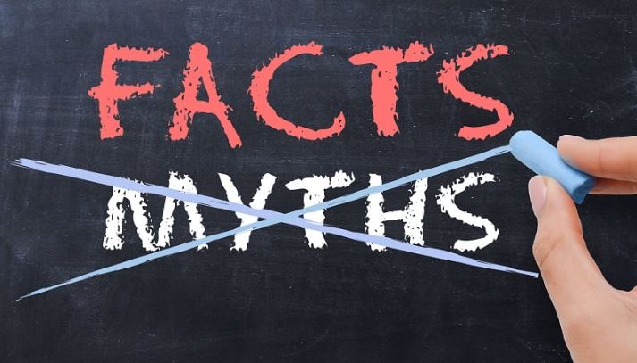 Hand crossing out myths and highlighting facts text on chalkboard, debunking native plant misconceptions